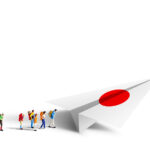 Miniature backpackers walking to the paper Japan airplane on white background