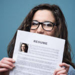 Young woman hiding behind her resume
