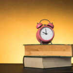 Symbolic hard study is powerful to succeed, concept with book and alarm clock. Time in business and quality